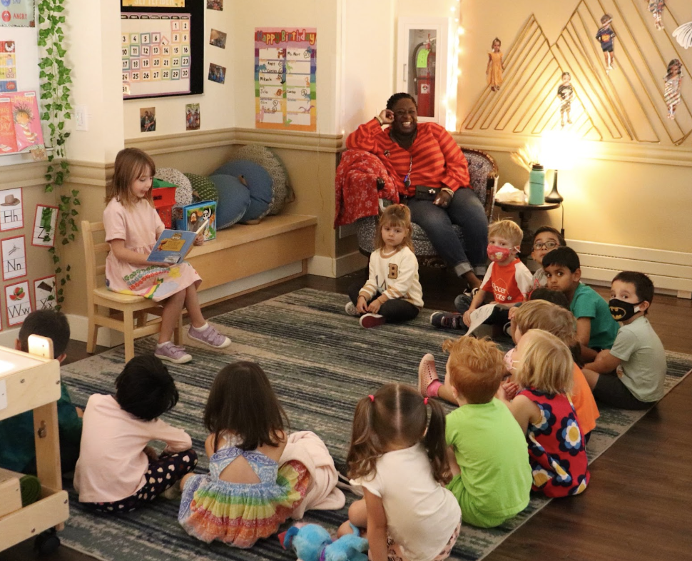 A Kindergarten student reads aloud to her classmates in the mixed-age Preschool-Kindergarten class